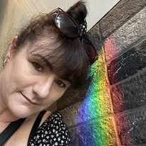 Nicole standing beside a rainbow mural